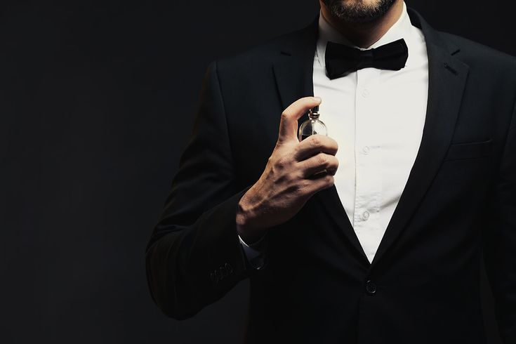 Man in a black tuxedo with a bow tie against a dark background