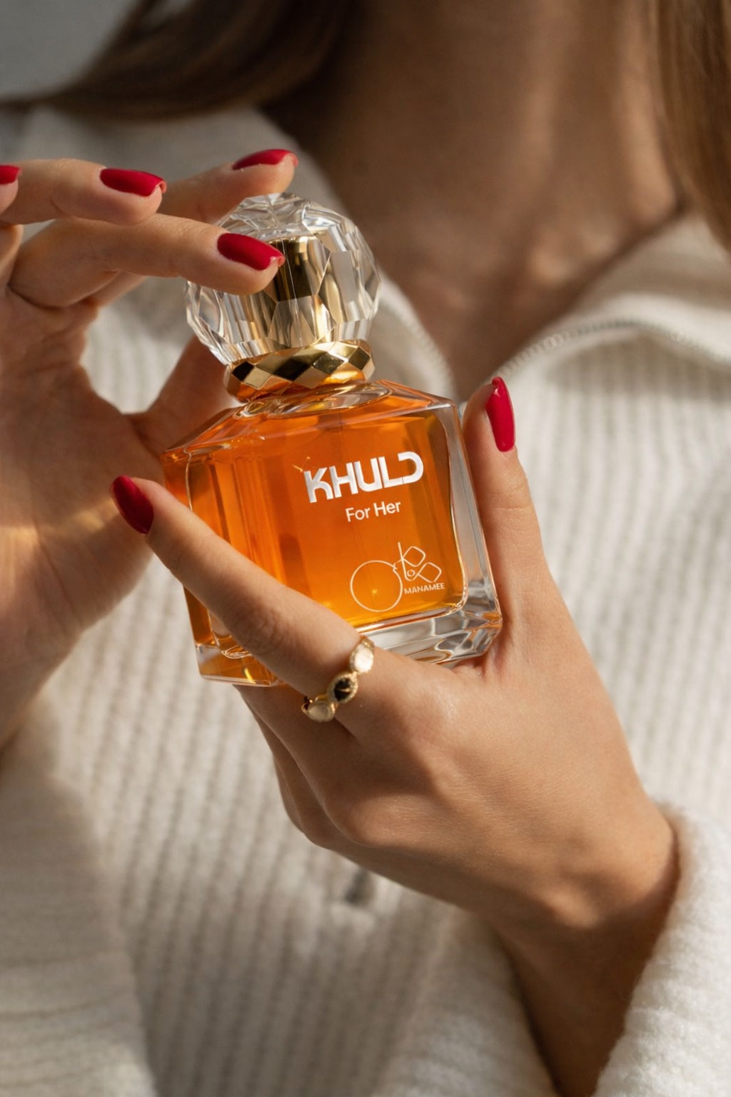 Person holding a perfume bottle labeled 'KHUL' with a blurred background
